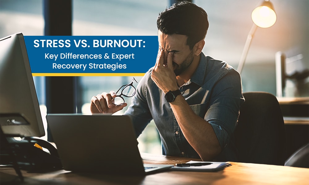 Stressed man at work holding his head with glasses in hand, illustrating the difference between stress and burnout in a modern office setting. 