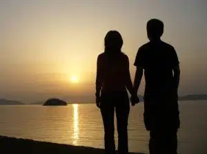 happy couple holding hands at sunset on a beach can benefit from marriage counseling