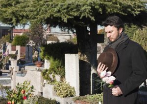 a man grieves for his child at a cemetery